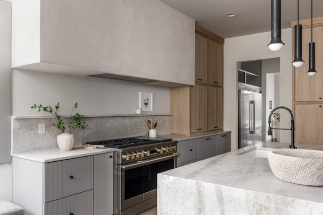 kitchen featuring decorative light fixtures, sink, backsplash, gray cabinetry, and high quality appliances