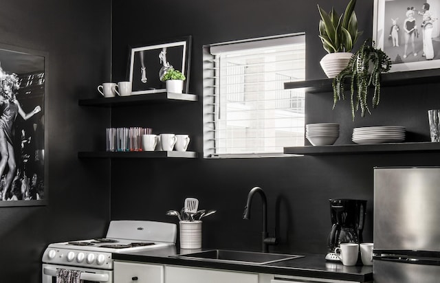 kitchen featuring sink, white electric range oven, and stainless steel refrigerator