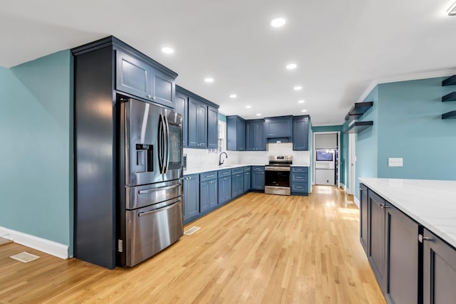 kitchen featuring backsplash, appliances with stainless steel finishes, sink, and light hardwood / wood-style flooring