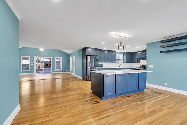 kitchen featuring a center island, appliances with stainless steel finishes, blue cabinetry, and light hardwood / wood-style flooring