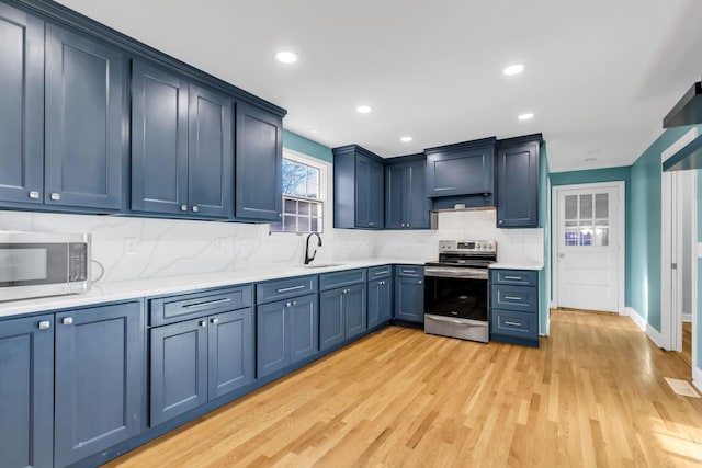 kitchen featuring appliances with stainless steel finishes, decorative backsplash, sink, blue cabinetry, and light hardwood / wood-style flooring