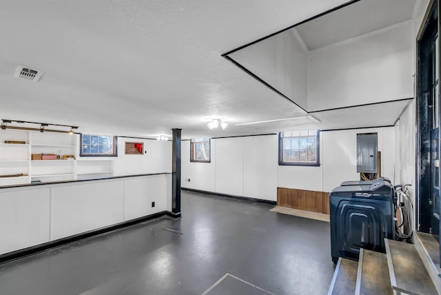 basement featuring a textured ceiling and electric panel