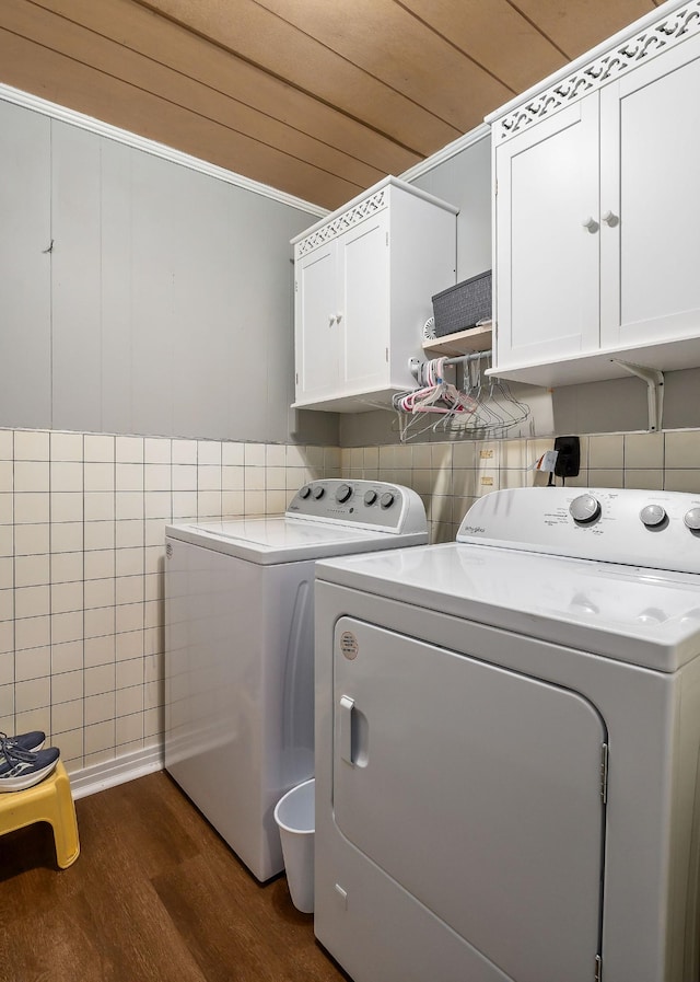 washroom with dark hardwood / wood-style flooring, washing machine and clothes dryer, and cabinets