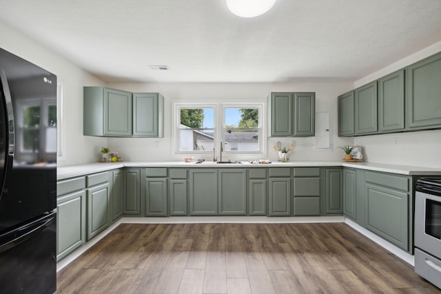 kitchen featuring dark hardwood / wood-style floors, sink, green cabinets, stainless steel electric range oven, and black refrigerator