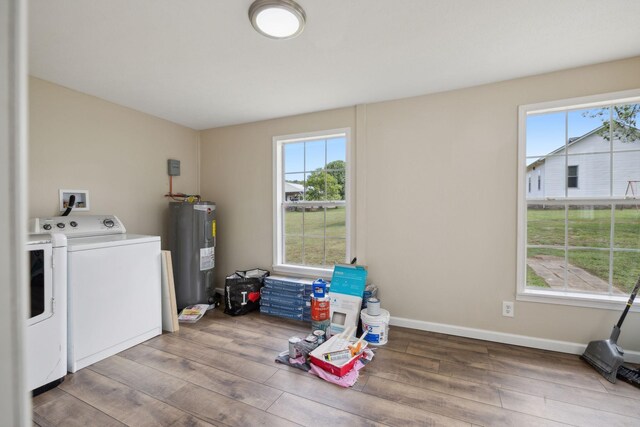 clothes washing area with separate washer and dryer, a wealth of natural light, wood-type flooring, and electric water heater