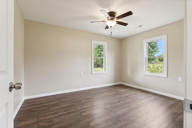 empty room with ceiling fan, a wealth of natural light, and dark hardwood / wood-style floors