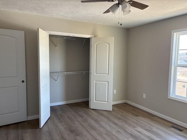 unfurnished bedroom featuring a textured ceiling, ceiling fan, a closet, and hardwood / wood-style floors