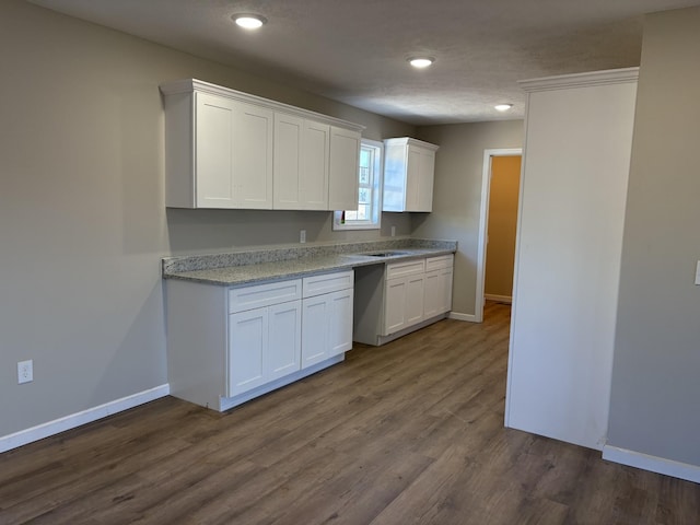 kitchen with light stone counters, white cabinetry, dark hardwood / wood-style floors, and a textured ceiling