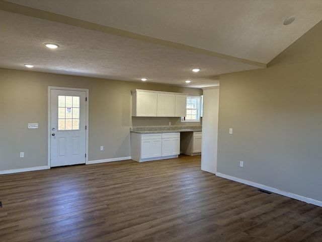 kitchen featuring vaulted ceiling, dark wood-type flooring, white cabinetry, and a healthy amount of sunlight