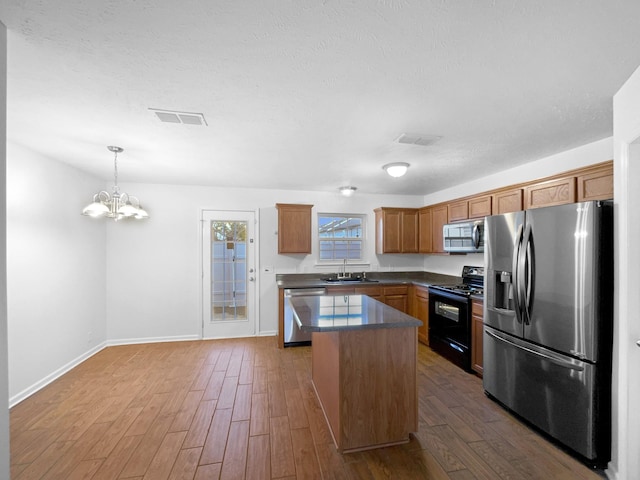 kitchen featuring pendant lighting, dark hardwood / wood-style flooring, sink, appliances with stainless steel finishes, and a kitchen island