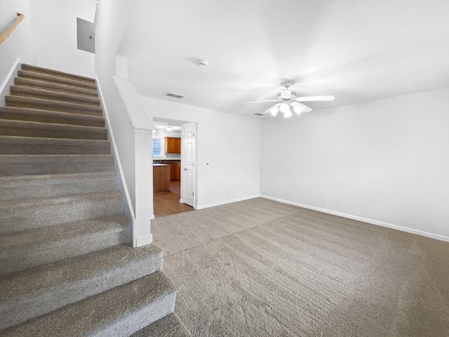 stairway with ceiling fan and carpet