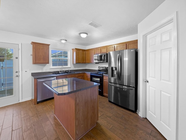 kitchen featuring sink, dark hardwood / wood-style flooring, a center island, and appliances with stainless steel finishes