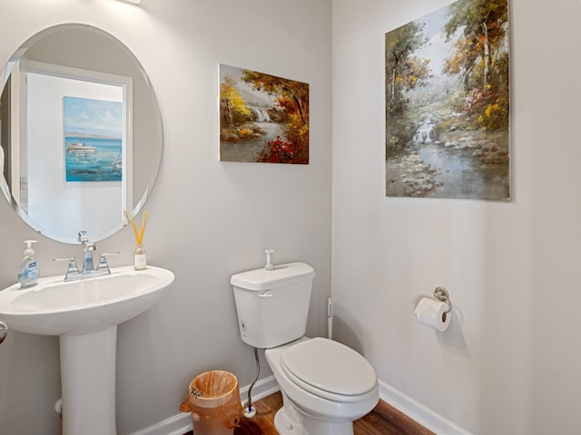 bathroom featuring toilet, sink, and hardwood / wood-style flooring
