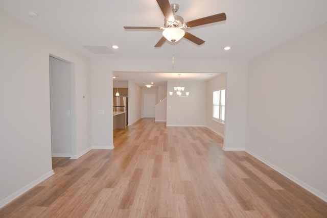 unfurnished living room featuring light hardwood / wood-style floors and ceiling fan with notable chandelier