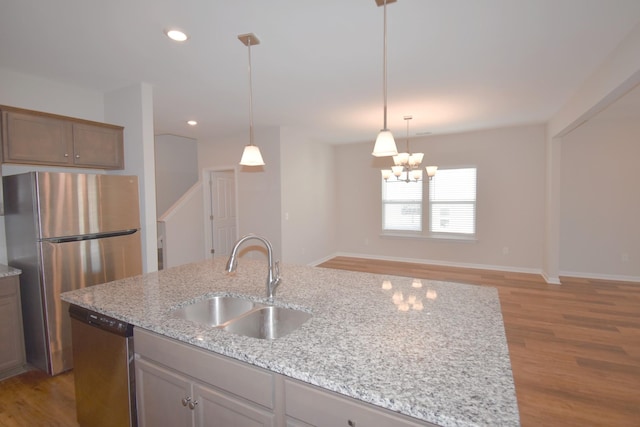 kitchen featuring light stone countertops, sink, appliances with stainless steel finishes, and an island with sink