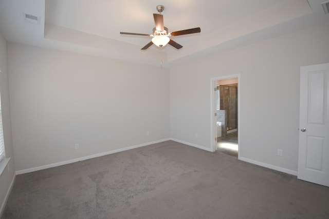 carpeted empty room with ceiling fan and a raised ceiling