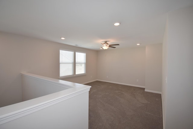 empty room with ceiling fan and dark colored carpet