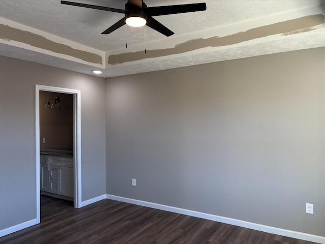 spare room featuring ceiling fan, dark wood-type flooring, and a textured ceiling