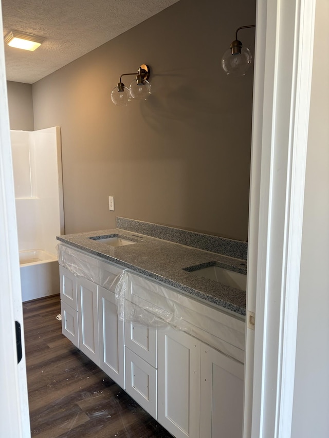 bathroom with vanity, wood-type flooring, a textured ceiling, and shower / tub combination