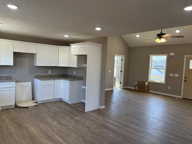 kitchen with lofted ceiling, white cabinetry, stone countertops, dark hardwood / wood-style floors, and ceiling fan