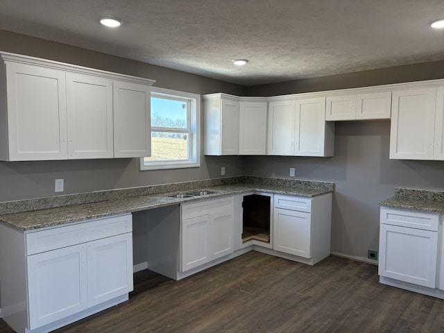 kitchen with a textured ceiling, white cabinetry, sink, dark hardwood / wood-style floors, and stone counters