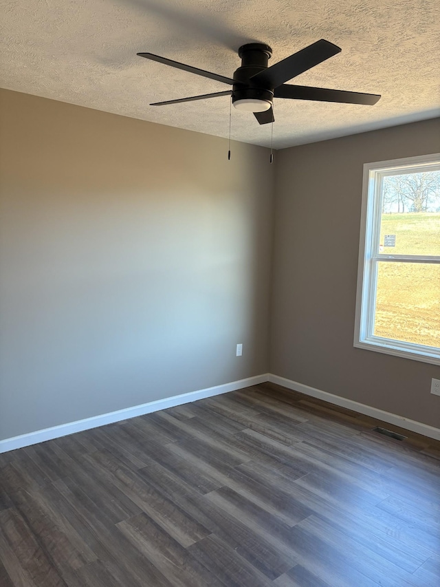 empty room with a textured ceiling and dark hardwood / wood-style floors