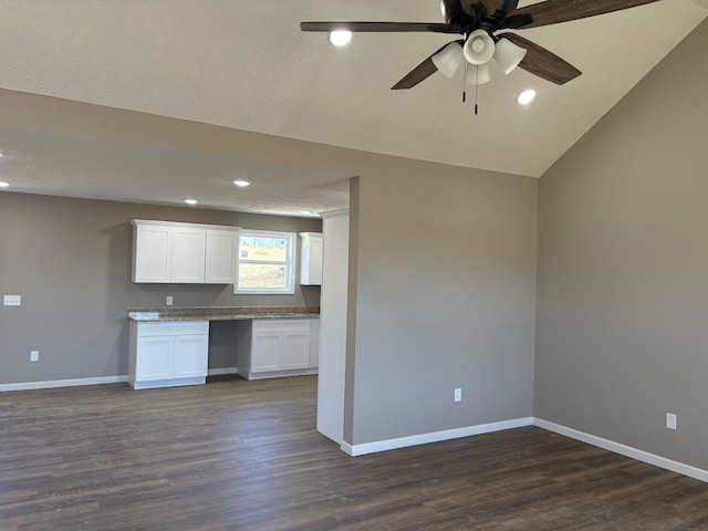 kitchen with ceiling fan, dark wood-type flooring, lofted ceiling, built in desk, and white cabinets