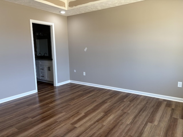 spare room featuring dark wood-style floors, a textured ceiling, and baseboards