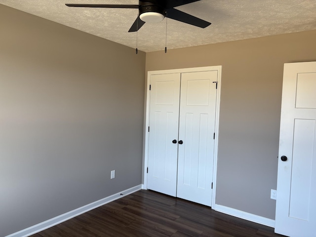 unfurnished bedroom featuring a closet, dark wood-type flooring, ceiling fan, a textured ceiling, and baseboards