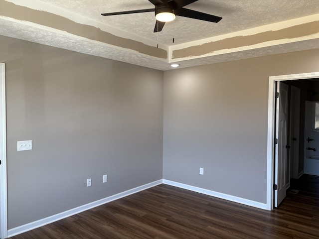 empty room featuring dark wood-style floors, ceiling fan, a textured ceiling, and baseboards