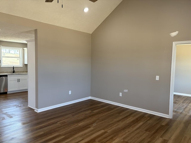 unfurnished room with dark wood-style floors, vaulted ceiling, a ceiling fan, and baseboards