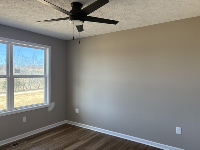 unfurnished room featuring baseboards, visible vents, dark wood finished floors, ceiling fan, and a textured ceiling