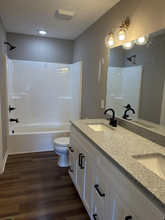 bathroom featuring toilet, a sink, visible vents, tub / shower combination, and double vanity