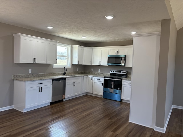 kitchen with stainless steel appliances, dark wood-style flooring, white cabinets, and a sink