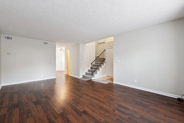 empty room with dark wood-type flooring and a textured ceiling