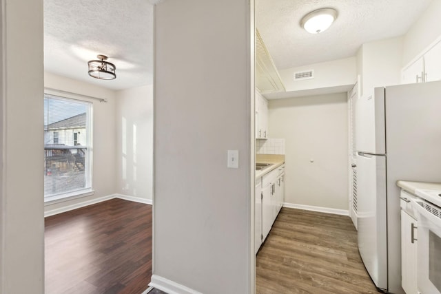 kitchen featuring a textured ceiling, dark wood-type flooring, white cabinetry, and tasteful backsplash