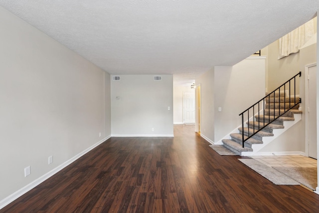 unfurnished room with a textured ceiling and dark wood-type flooring