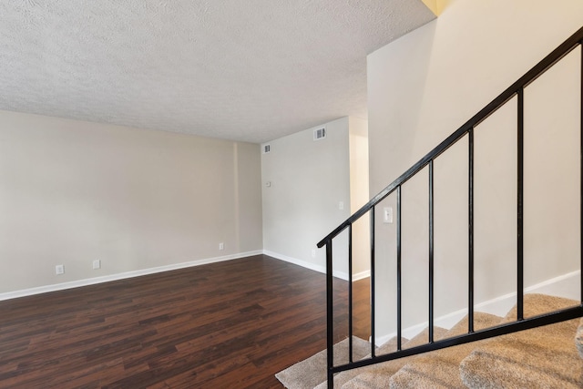 stairway featuring a textured ceiling and hardwood / wood-style floors