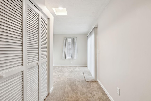 hallway with light colored carpet and a textured ceiling