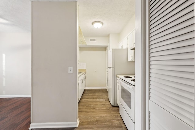 kitchen featuring white appliances, white cabinets, dark hardwood / wood-style flooring, and a textured ceiling