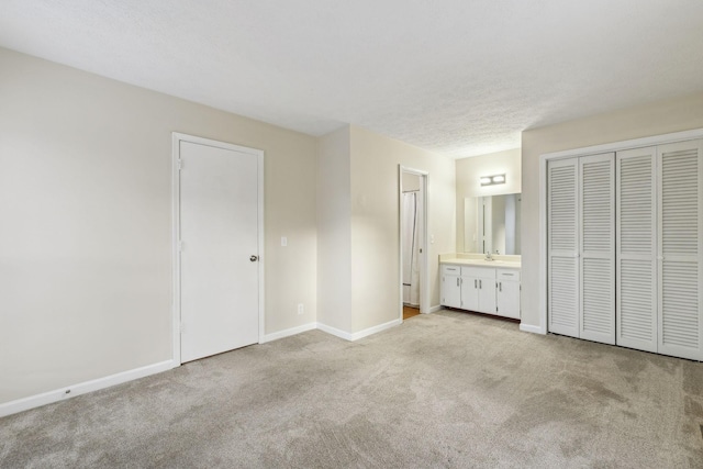 unfurnished bedroom with sink, ensuite bathroom, a closet, and light carpet