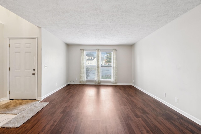 empty room with dark wood-type flooring and a textured ceiling