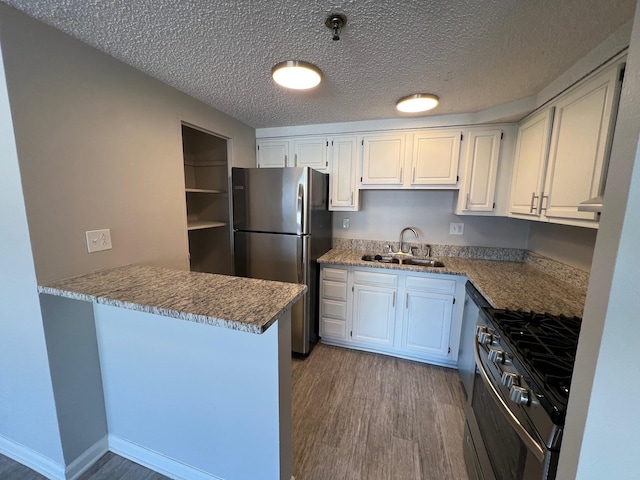 kitchen featuring kitchen peninsula, stainless steel appliances, white cabinetry, and sink