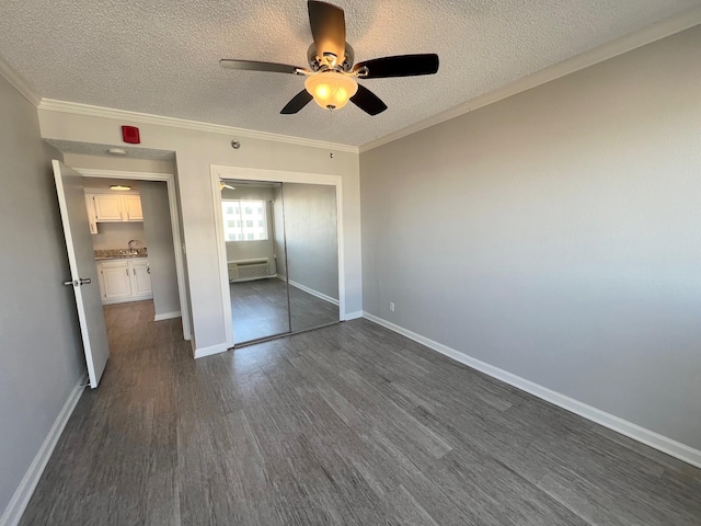 unfurnished bedroom with dark hardwood / wood-style flooring, a closet, ceiling fan, crown molding, and a wall mounted air conditioner