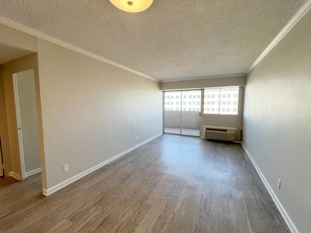 spare room with wood-type flooring, ornamental molding, a textured ceiling, and a wall mounted AC