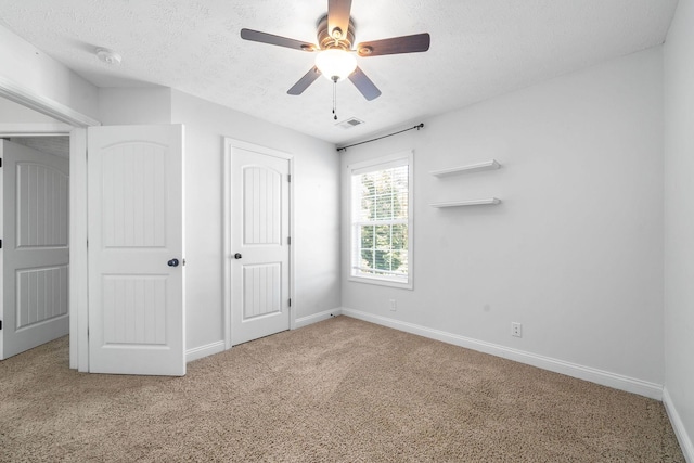 unfurnished bedroom featuring ceiling fan, carpet, and a textured ceiling