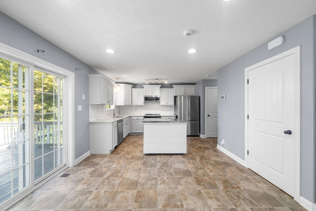 kitchen with stainless steel appliances, decorative backsplash, a center island, range hood, and sink