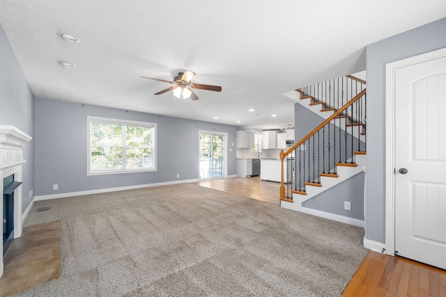 unfurnished living room with ceiling fan, sink, a textured ceiling, and carpet flooring