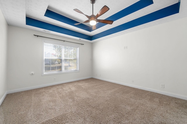 carpeted empty room with ceiling fan and a tray ceiling