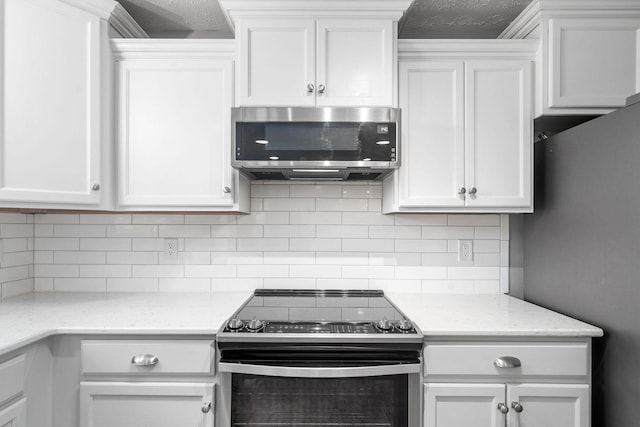 kitchen with stainless steel appliances, backsplash, white cabinets, and light stone counters